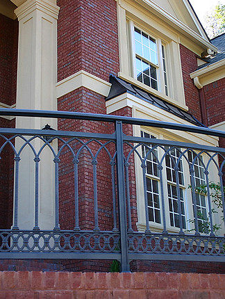 Декоративен парапет с визия на ковано желязо, монтиран върху тухлена тераса на класическа сграда.