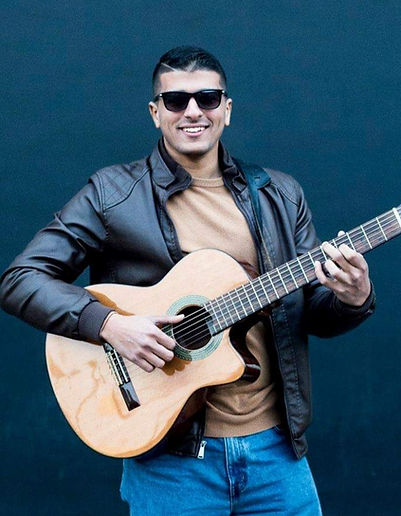 Mando Rock Smiling While Playing the Guitar