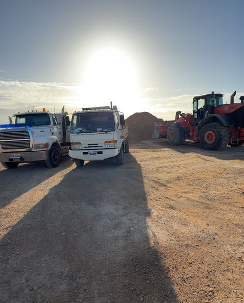 Dirt mound with two trucks and tractor grader for earth moving and bulk haulage project