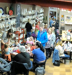 Customers gather inside a shop with shelves full of items and a staircase.