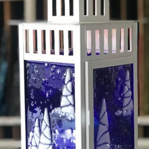 White metal lantern with blue fused glass panels, winter scene details.