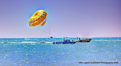 Parasailing over the clear blue waters of Lake Huron, boat below.