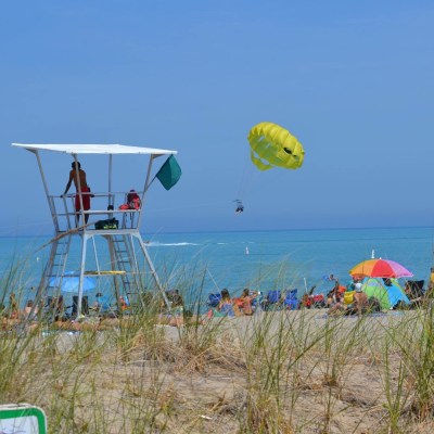 Lifeguard tower on the beach with a parasail flying in the distance over Lake Huron