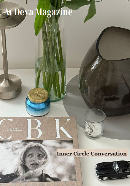 Coffee table with CBK magazine, blue jar, vase with leaves, candle, and toy car. Text: A Deya Magazine, Inner Circle Conversation.
