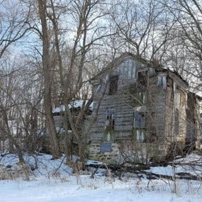 Old wooden building in winter with snow and bare trees