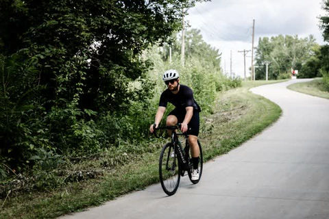 Person riding a bicycle along a winding path lined with trees