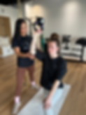 Physio helping patient with a bottoms up kettlebell press for shoulder rehab, in boutique gym