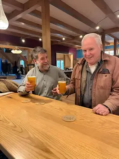 two men drinking beer at a bar