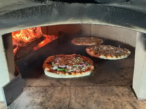 3 pizzas baking in a wood-fired pizza oven