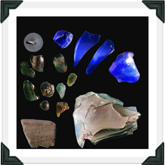 Glass shards in shades of green, a few pieces of blue, pieces of the clay pots and a small 18th-century copper and brass clothing button.