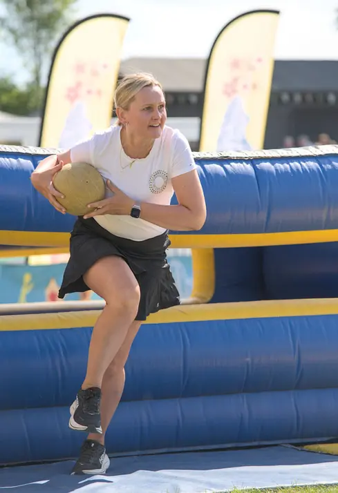 photograph of a woman taking part in a competative event with a ball under her arm getting ready to sprint