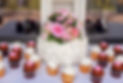 Wedding cake with pink flower arrangement topper with white, red and pink cupcakes surrounding