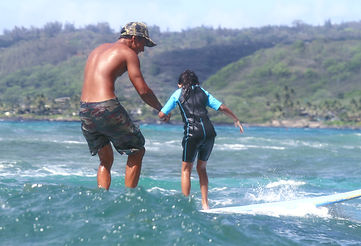 Instructor teaching young kid how to Surf