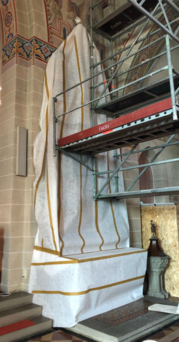 Staubdichte Verpackung eines Seitenaltars zum Schutz der empfindlichen Oberflächen, während im Kirchenschiff Putzarbeiten an den Wänden stattfinden.