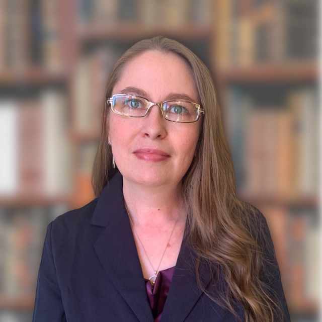 Headshot of a female attorney with long hair and glasses, smiling intelligently