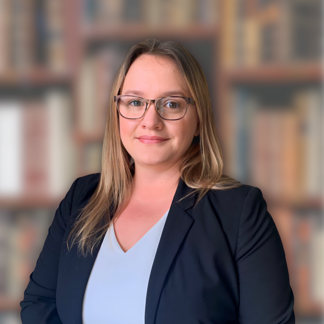 Headshot of a female attorney with medium-length hair and glasses, smiling intelligently