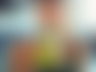 Woman in a gym drinks a green smoothie from a clear bottle. She wears a dark green tank top, creating a refreshed mood. Bright, blurred background.