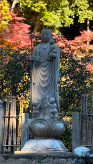お地蔵さんが真ん中に背景に紅葉した葉っぱ