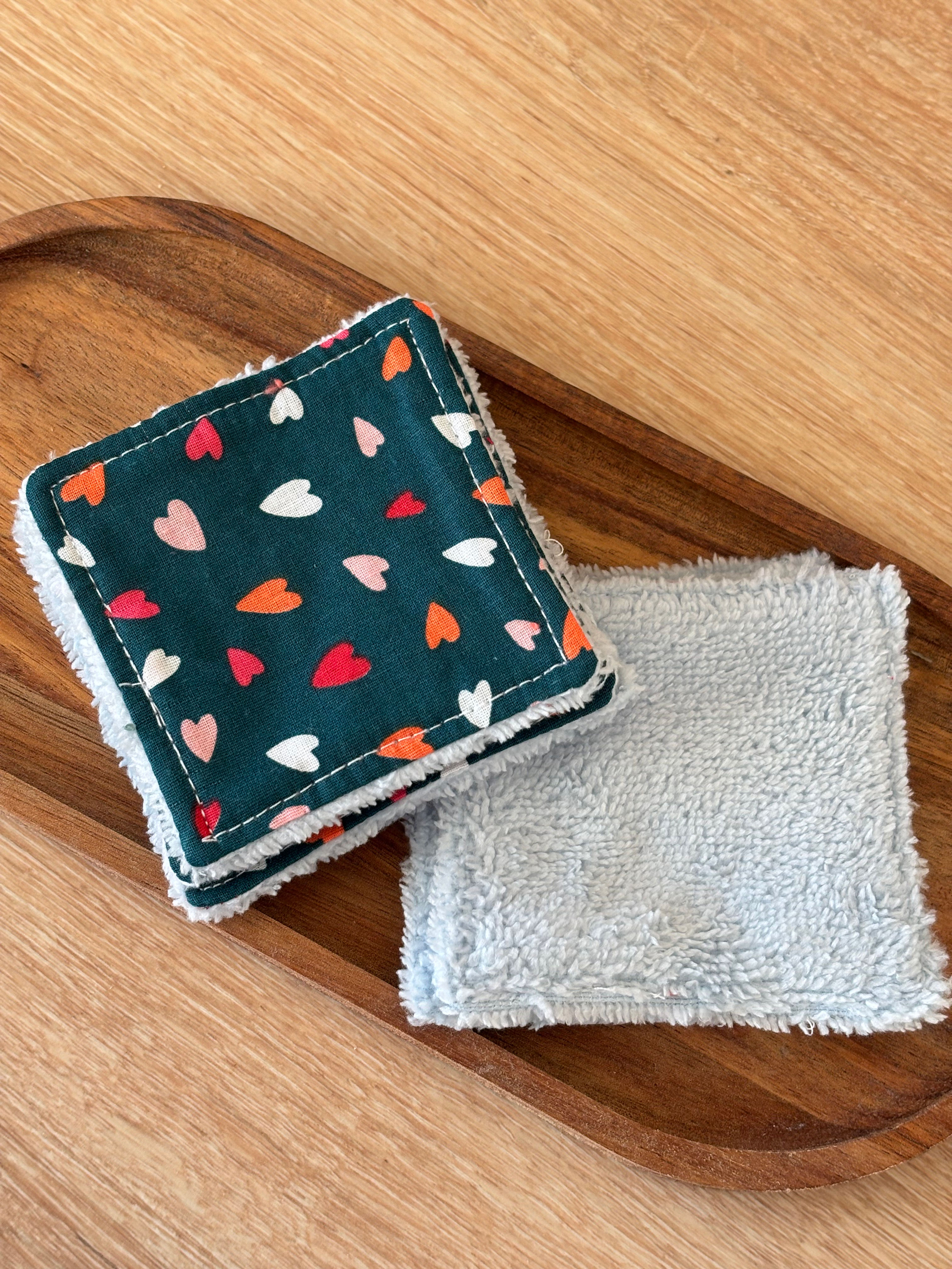 Deux carrés de démaquillant avec des motifs de coeurs posés sur un plateau.