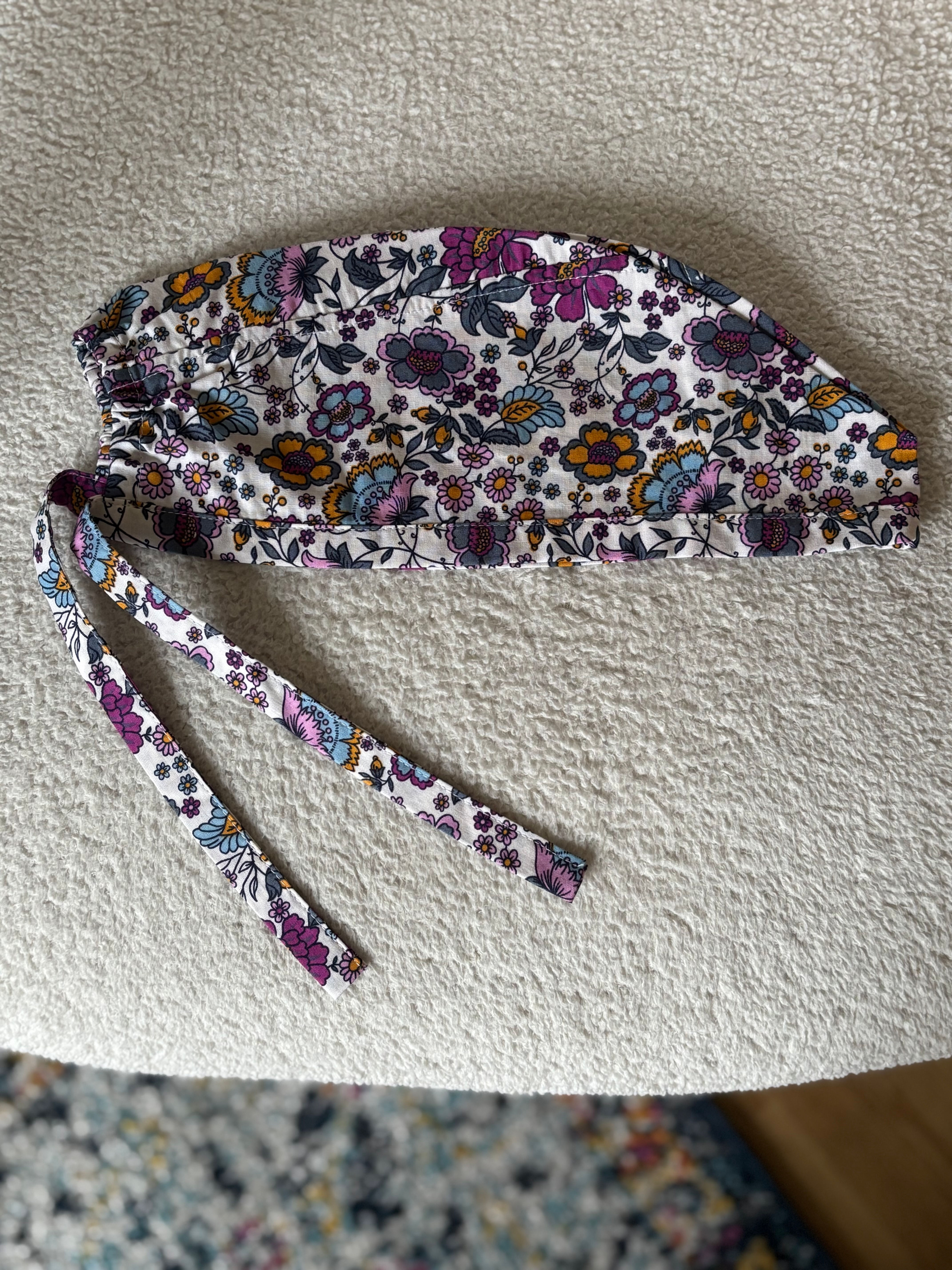 Casquette de chirurgie fleurie posée sur une surface, Calot chirurgical, vue de dessus.