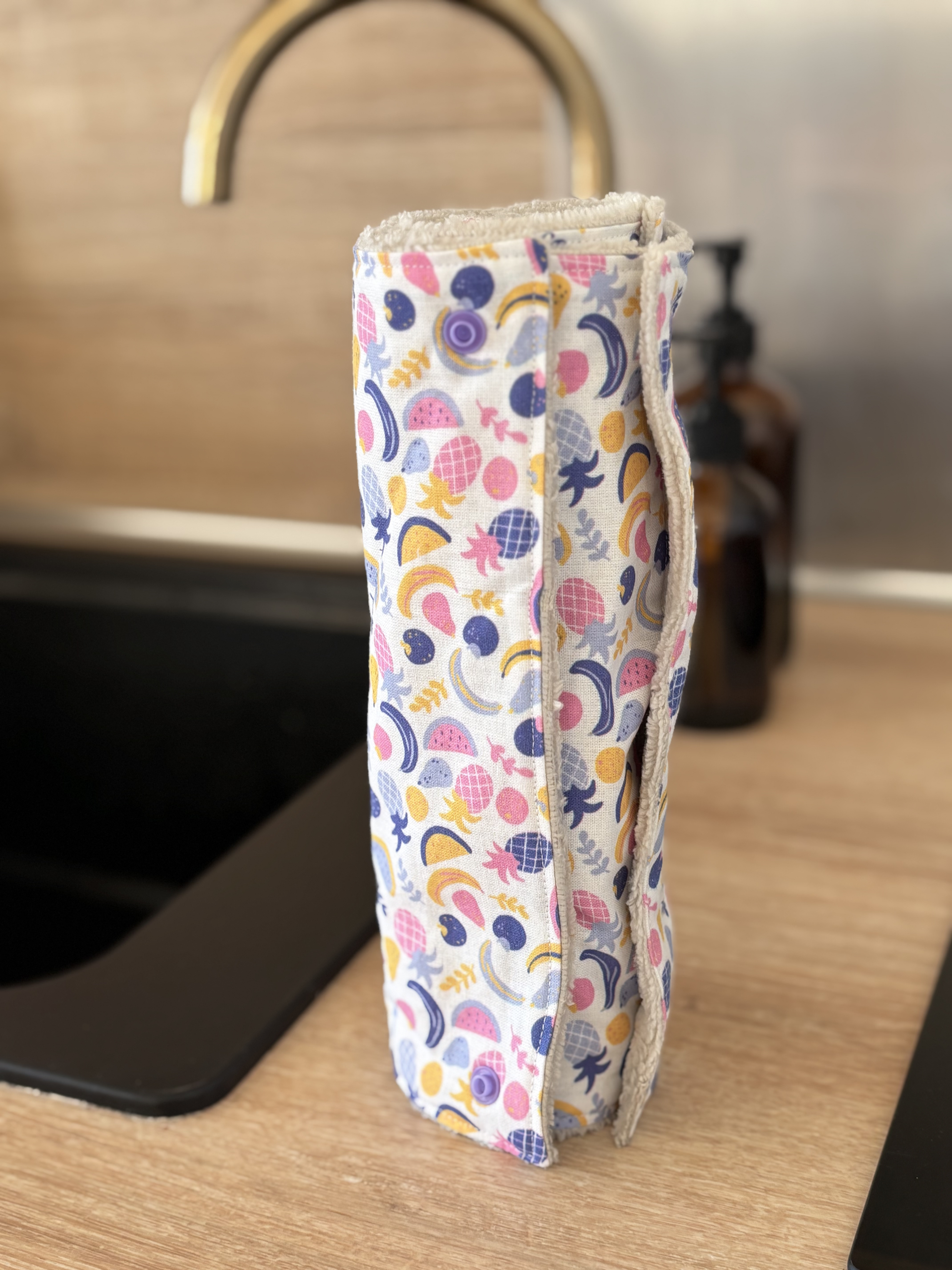 Rouleau de chiffon imprimé fruits, sur un comptoir de cuisine, lavable.