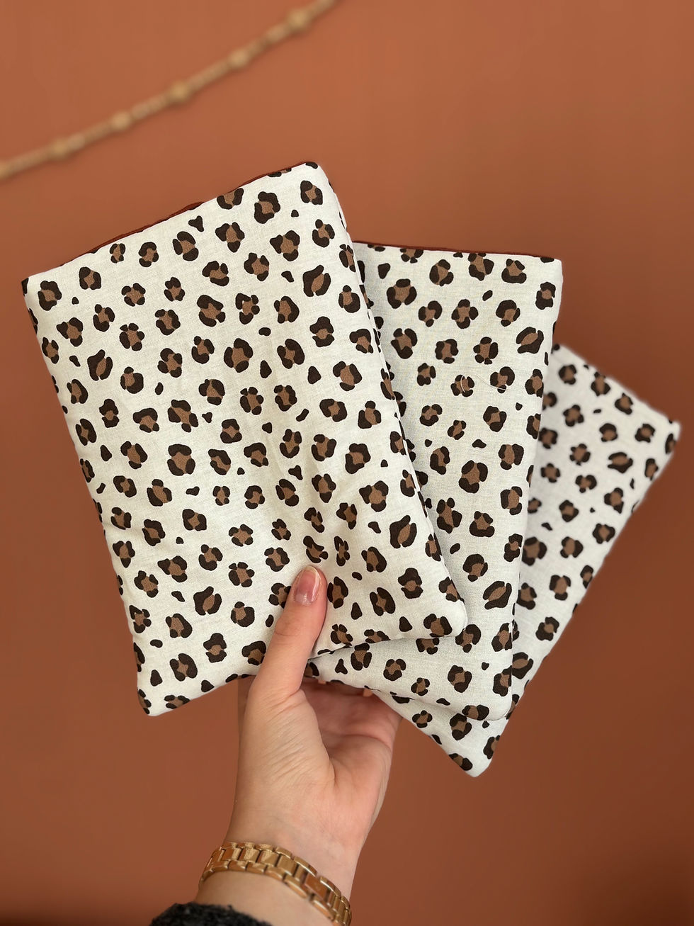 Main tenant trois calot chirurgicals avec motif léopard sur fond marron.