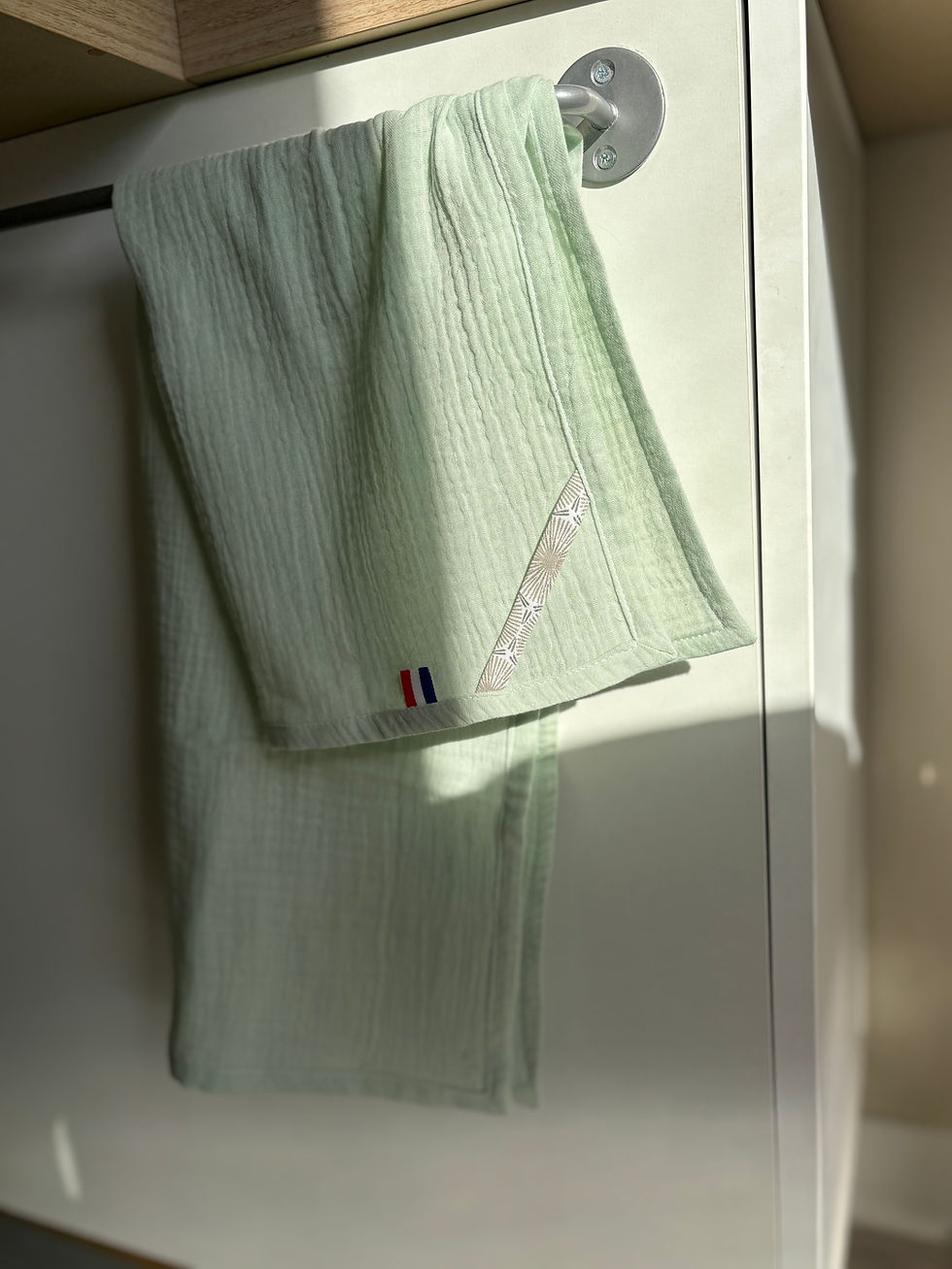 Serviette verte pliée sur une barre avec un logo tricolore, détail