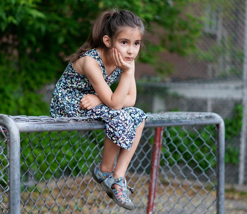 Girl sitting along atop a soccer goal.