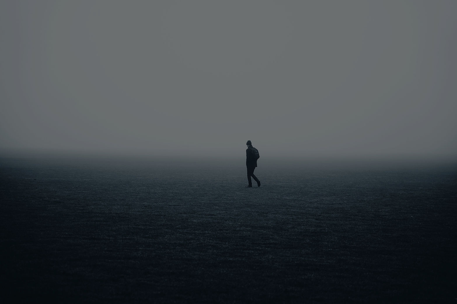 Silhouette of a man walking alone on a foggy open field._edited.jpg