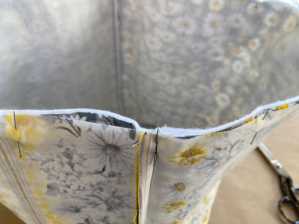 Preparing to sew by aligning the seams and pinning around the top edge of the fabric piece.