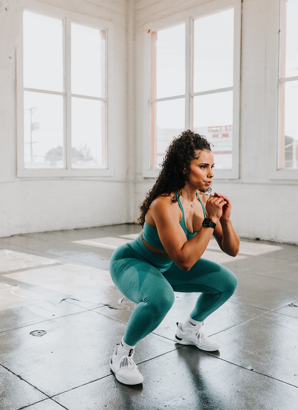 Person practicing a deep squat to enhance hip and ankle mobility in a well-lit room.