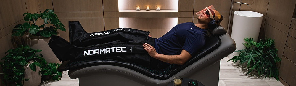 Homem usando botas compressivas normatec e máscara de Biohacking para tratamento facial alta tecnologia