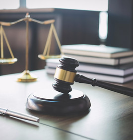 Picture of a gavel resting on a block with the scales of justice in the background