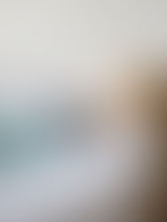 A dog leaning over a couch to sniff a newborn baby wrapped in a blue swaddle.