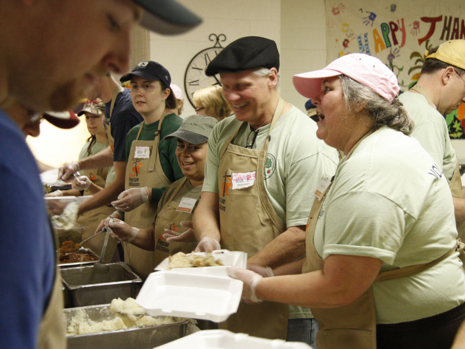 people wearing aprons putting food on styrofoam plates