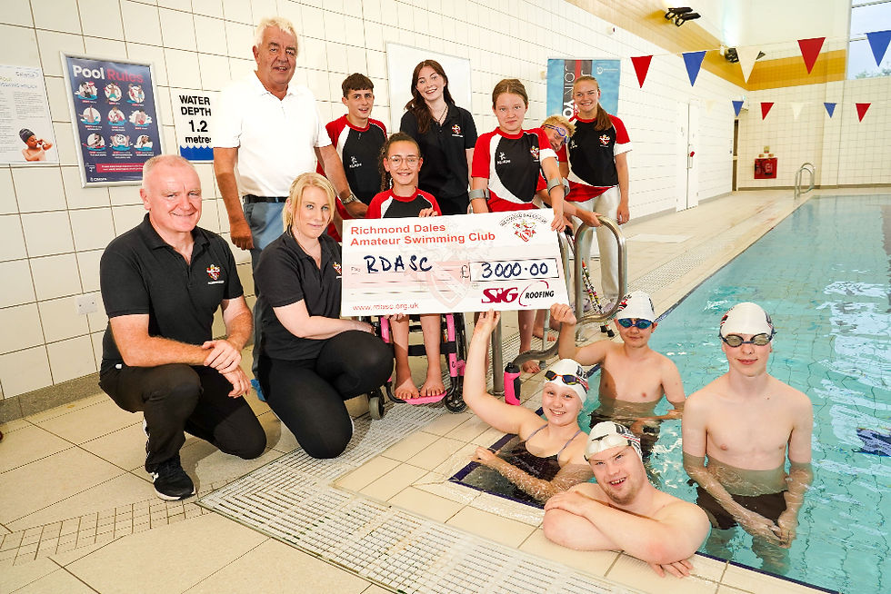 the swimming team next to the pool with a big cheque for £3000