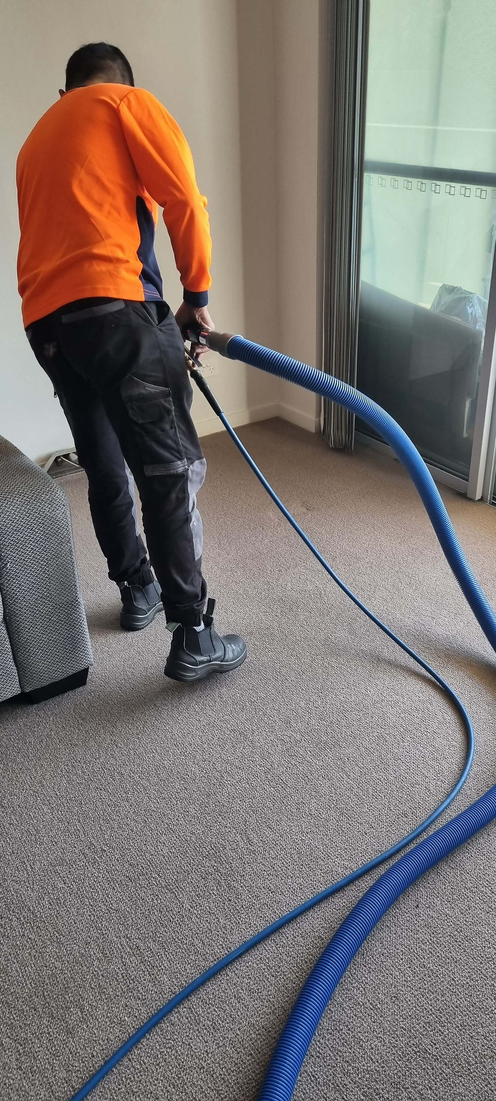 a mould removal technician removing flood water from carpet with a commercial water extraction machine