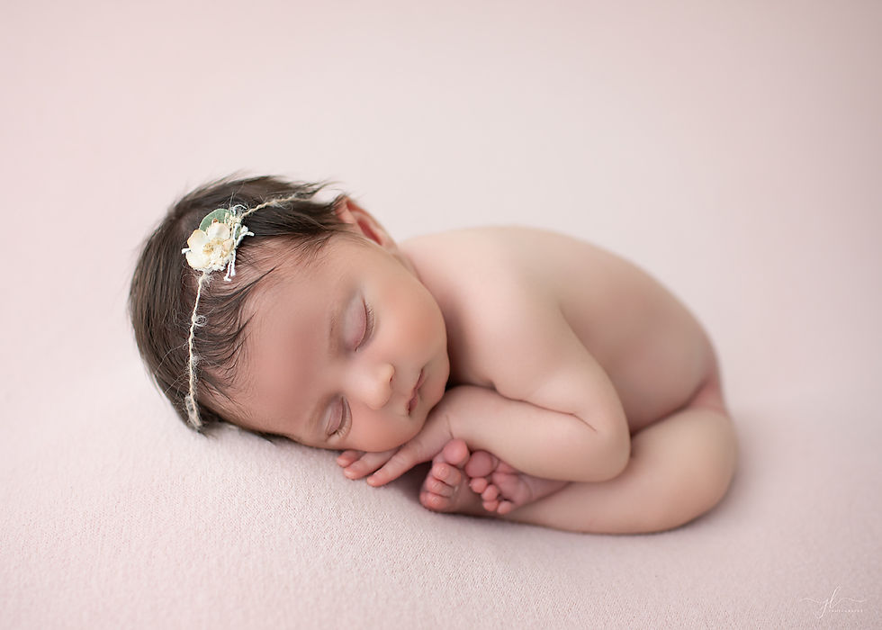 Newborn baby girl sleeping on a soft pink backdrop during her session in London, Ontario.