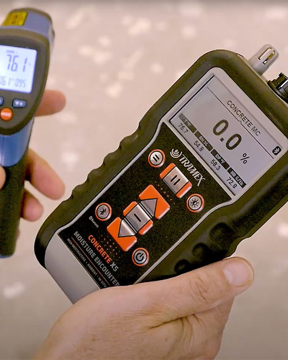 A close-up side-by-side shot of a professional technician performing advanced concrete moisture testing on a garage floor using a digital moisture meter displaying a reading of 4.2 percent