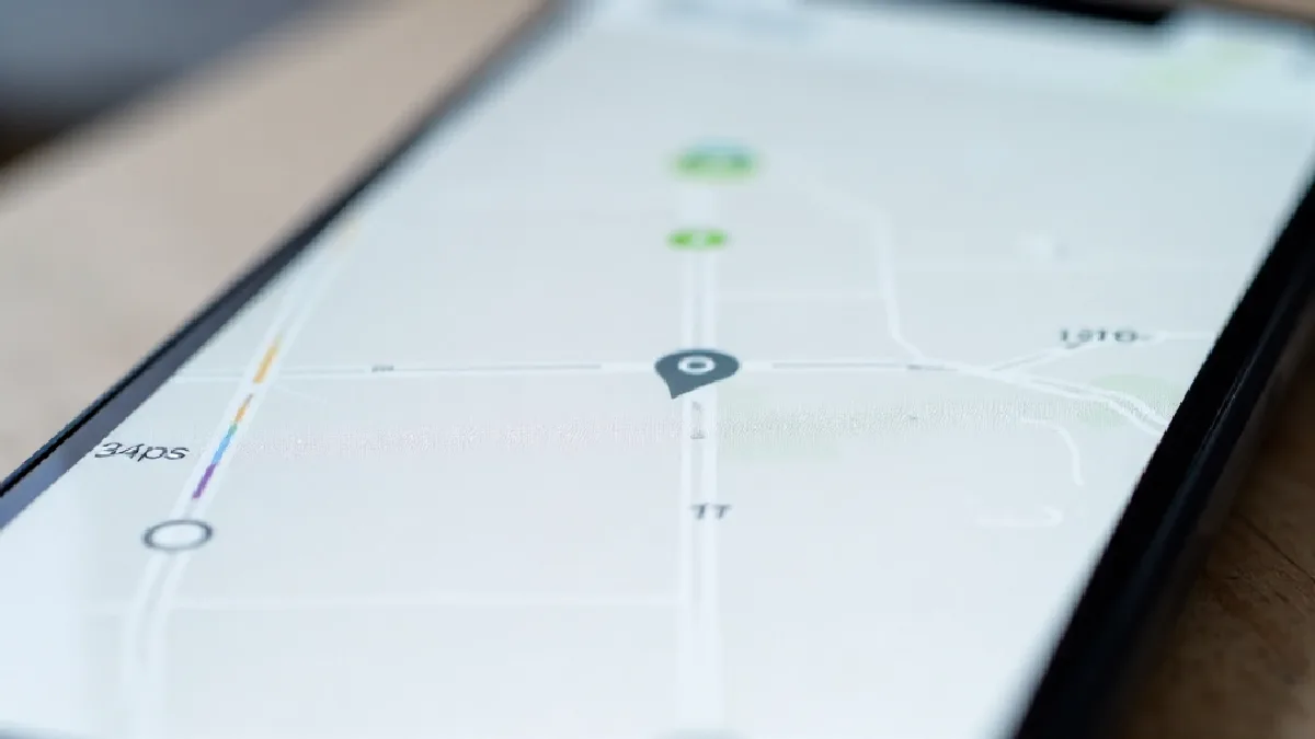Smartphone displaying GPS delivery routing software resting on a dashboard, depicting cannabis logistics technology and delivery regulations.