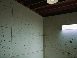 A diffuse red laser reflection forms ambiguous geometric speckles on a wall beside a distant observer.