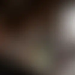 A handcrafted glass bong stands inside a warmly lit Las Vegas glass-art studio surrounded by tools and furnace glow.