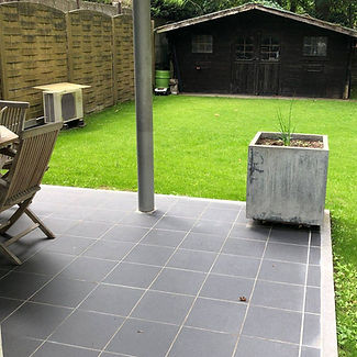 Tuinaanleg met terras in steen en houten afsluiting