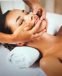 Vrouw met gesloten ogen ontvangt gezichtsmassage, ontspanning en huidverzorging.