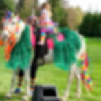 Girl wearing bunny ears standing next to white horse wearing bunny ears
