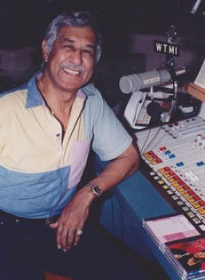 Smiling man in WTMI radio studio with mic and mixing board