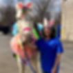 Girl wearing bunny ears standing next to white horse wearing bunny ears