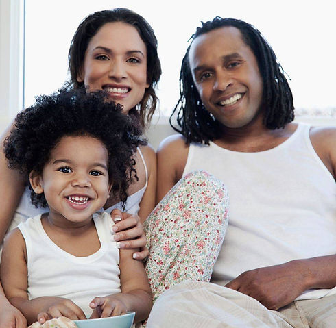 A picture of a family including a mother, father and son. They are wearing a white shirt. The family is smiling