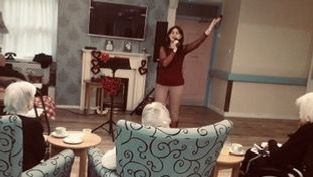 resident dancing, singing with flower and wearing hat