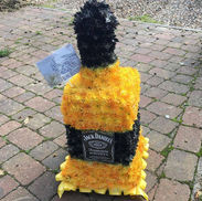 Floral Jack Daniels bottle with label against a brick background. Bentley Blooms